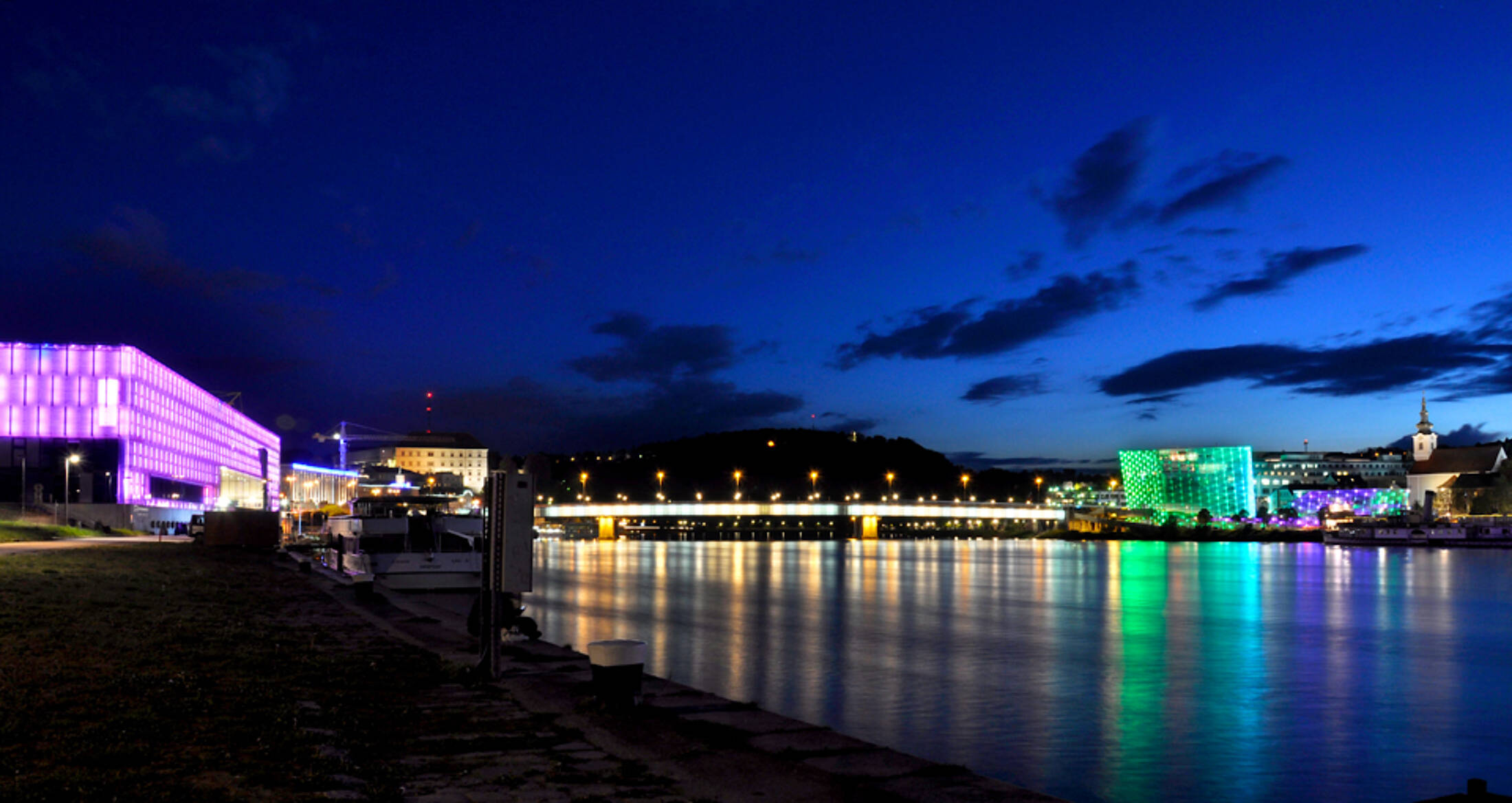 Ein buntes Lichterspiel an der Donau nach Sonnenuntergang.